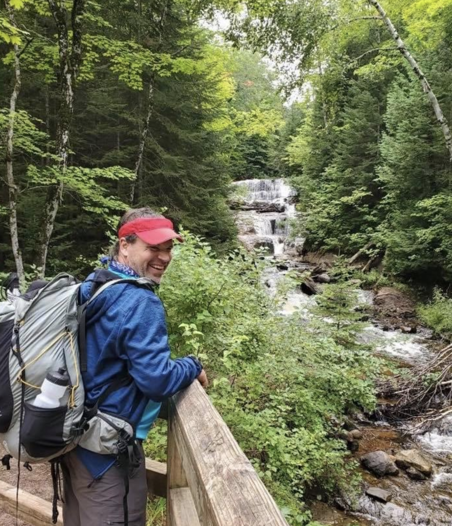 Rue standing on a bridge with stream and waterfall in the background